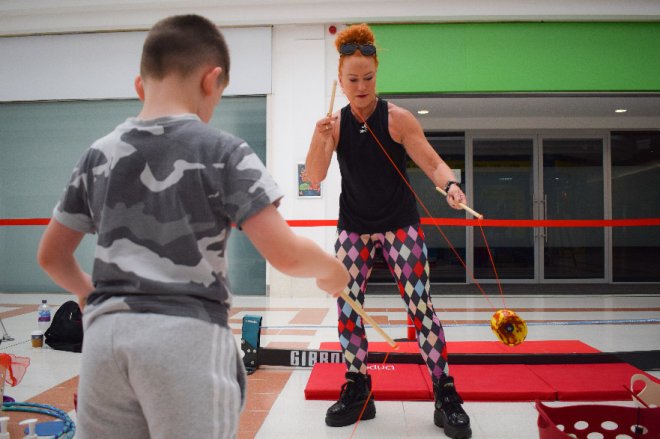 A boy is taught how to diablo by a circus performer as part of a circus skills workshop
